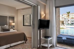 a bedroom with a bed and a tv and a pool at Atlantica Aeneas Resort in Ayia Napa