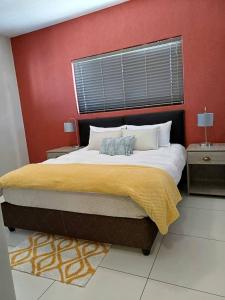 a bedroom with a large bed with a red wall at MERENSKY Windhoek in Windhoek