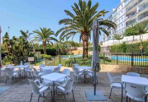 a patio with white tables and chairs and a pool at Luxury Apartment/ Sea views/Pool/Gym in San Jorge