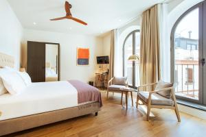 um quarto com uma cama, uma cadeira e janelas em Casa Alhaja by Shiadu em Sevilha