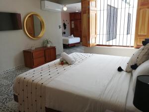 una camera da letto con un grande letto bianco e uno specchio di Hotel Casa Piedad a Campeche