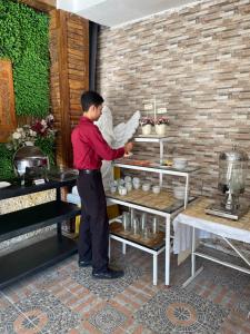 a man standing in a kitchen preparing food on a shelf at Votel Hotel De'Pratnya Kediri in Kediri
