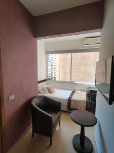 um quarto com uma cama, uma cadeira e uma janela em Bliss 3000 Furnished Studios em Beirute