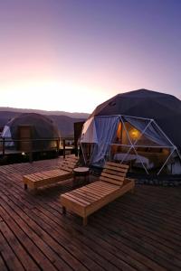 a group of tents sitting on a deck with benches at Glamping Tafí del valle in Tafí del Valle