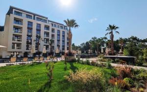 un hôtel avec une pelouse, des chaises et des palmiers dans l'établissement Luxury Apartments in complex Azur - next to the BEACH !, à Saints Constantine et Helena