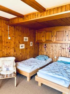 two beds in a room with wooden walls at Chalet Tobeleck - CharmingStay in Flumserberg