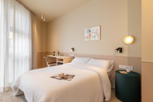 Un dormitorio con una gran cama blanca y una mesa en La Florida Suites by Olala Homes, en Hospitalet de Llobregat
