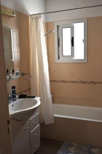 uma casa de banho com um lavatório, uma banheira e uma janela em Отдыхайте с удовольствием em Pafos