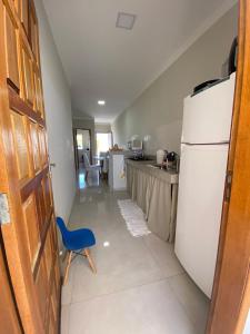 a kitchen with a white refrigerator and a blue chair at Casa Prado Bahia in Prado