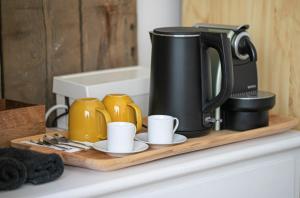 a coffee maker and cups on a wooden tray on a counter at Cozy Airport in Vecsés