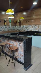 une cuisine avec un comptoir et un bar avec des chaises dans l'établissement Casa bairro Tiradentes, à Governador Valadares