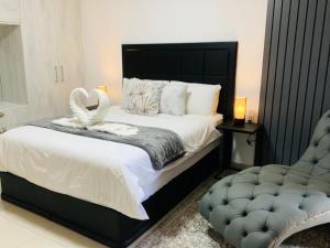 a bedroom with a large bed and a chair at Essence Lifestyle Self-Catering Accommodation in Windhoek