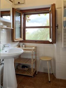 baño con lavabo, ventana y taburete en Il Colombaio, en Cavriglia