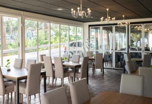 a dining room with tables and chairs and windows at Hostal Victoria in Altura