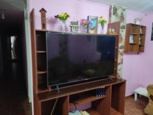 a large flat screen tv sitting on a wooden entertainment center at Flatshare Department in Baños