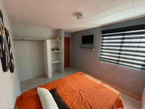 ein Schlafzimmer mit einem orangenen Bett und einem Fenster in der Unterkunft Casa Luxxury Celaya in Celaya