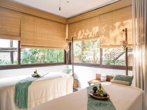 two beds in a room with windows at The Beach Tulum Hotel in Tulum