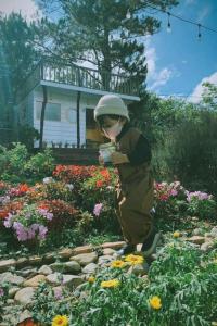 a young boy standing in a garden with flowers at Lưng Chừng House in Da Lat