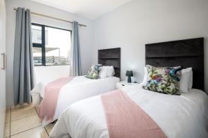a bedroom with two beds and a window at Lux Garden Ballito Groves 1101 in Ballito