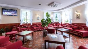 a waiting room with red couches and a tv at Galia in Druskininkai