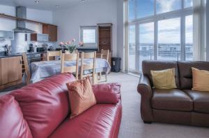 een woonkamer met een leren bank en een keuken bij The Penthouse - 3 Bedroom Apartment - Llanelli in Llanelli