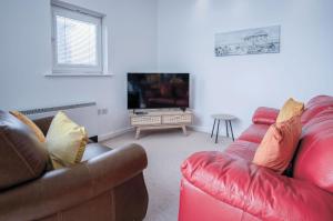 a living room with two couches and a flat screen tv at The Penthouse - 3 Bedroom Apartment - Llanelli in Llanelli