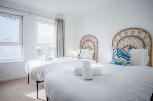 twee witte bedden in een kamer met twee ramen bij The Penthouse - 3 Bedroom Apartment - Llanelli in Llanelli