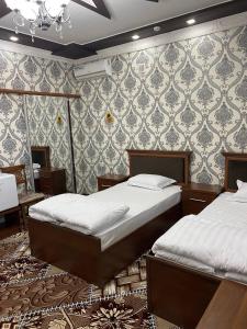 1 dormitorio con 2 camas y pared en VOSTOK HOTEL en Bukhara