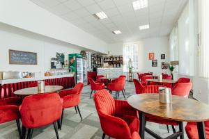 un restaurant avec des chaises rouges, des tables et un comptoir dans l'établissement Black M - Penzión, à Banská Štiavnica
