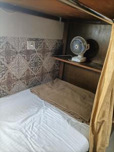 uma cama num quarto com uma ventoinha numa prateleira em Metro inn dormitory em Mumbai