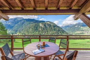 シャテルにあるBlack Diamond - Chalet - BO Immobilier- remises sur les forfaits de skis Châtel ou Portes du soleilの山の入ったポーチの木製テーブルと椅子