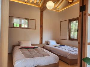 two beds in a room with two windows at IRIRU Luxury Hanok Stay - Eunpyung Hanok village in Seoul