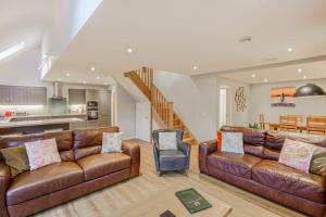 a living room with two leather couches and a kitchen at Lord Galloway 36 with Hot Tub in Newton Stewart