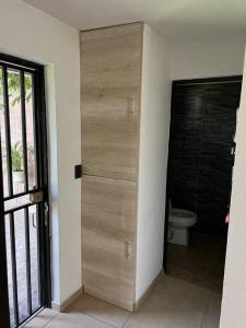 a bathroom with a toilet and a wooden door at Casa Deluxe Celaya in Celaya