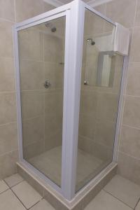 a shower with a glass door in a bathroom at The Suburban Guest House in Bloemfontein