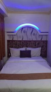 um quarto com uma cama com uma luz azul por cima em Votel Hotel De'Pratnya Kediri em Kediri