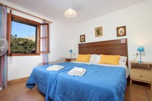 a bedroom with a bed with blue sheets and a window at Villa Camp Redo in Pollença +22 photos