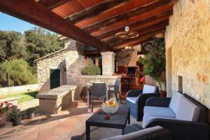 an outdoor patio with chairs and a stone fireplace at Villa Camp Redo in Pollença