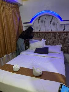 uma pessoa ao lado de uma cama com sapatos em Votel Hotel De'Pratnya Kediri em Kediri