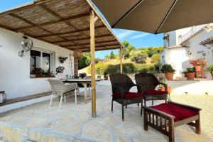 een terras met een tafel, stoelen en een parasol bij La Sureña in Alhaurín el Grande