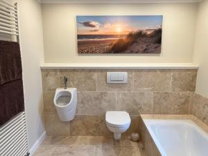 a bathroom with a toilet and a urinal and a bath tub at Ferienhaus Mayland in Humptrup