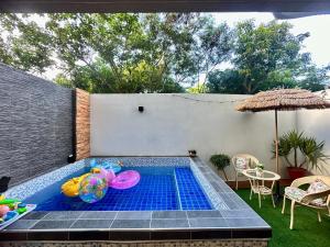 a small swimming pool in a backyard with a table and an umbrella at Kenting - Rest In Your Relax Time in Hengchun