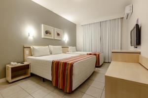 a hotel room with two beds and a flat screen tv at Hotel Pires in Balneário Camboriú