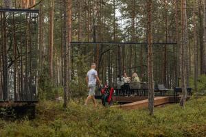 a man walking through a forest with a group of people at ÖÖD Hötels Lohusalu LEIDA & ENNO in Laulasmaa