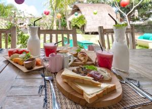 a wooden table with sandwiches and drinks on it at brothers bungalows in Jimbaran