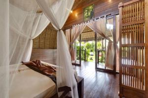 a bedroom with a bed with a canopy at brothers bungalows in Jimbaran