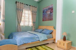 sypialnia z łóżkiem z niebieską pościelą i oknem w obiekcie Meraki home 3 w mieście Kampala
