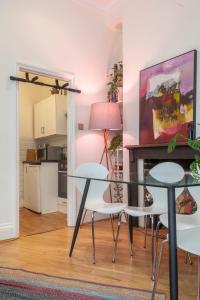 a dining room with a glass table and white chairs at Unique 1 BR flat btw Hammersmith & Fulham in London