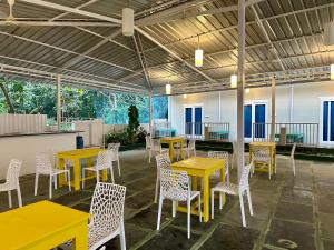 uma cafetaria com mesas amarelas e cadeiras brancas em Coco Hostel Goa em Palolem