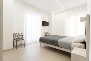 a white bedroom with a bed and a chair at Appartamento comfort-relax in Termoli